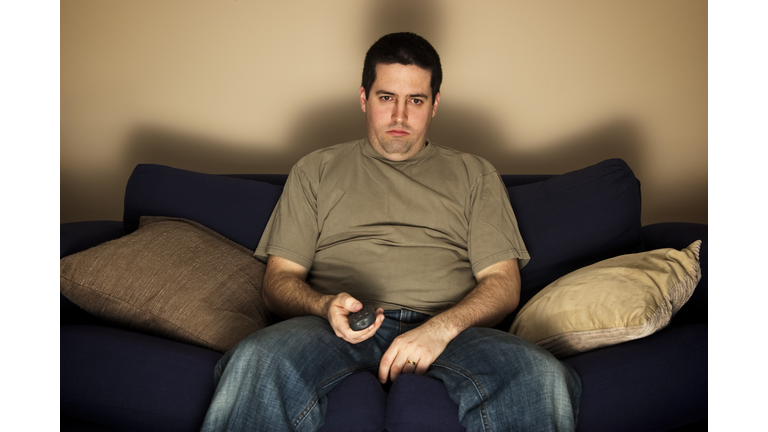 Bored, lazy, overweight man sits on the sofa