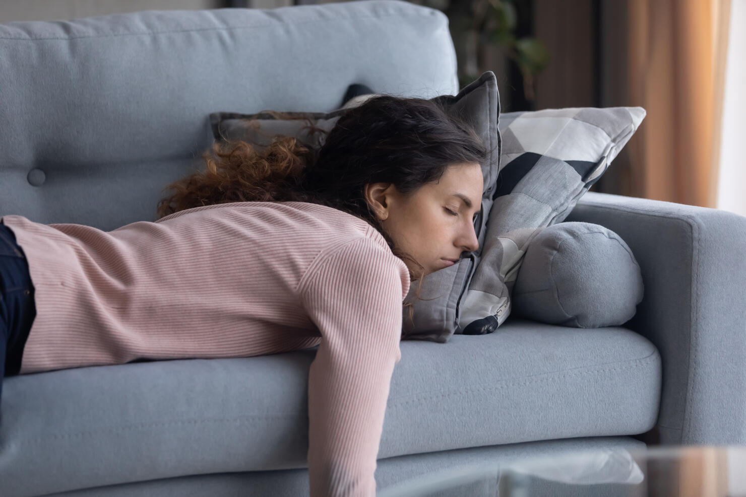 Tired young woman sleeping on couch at home