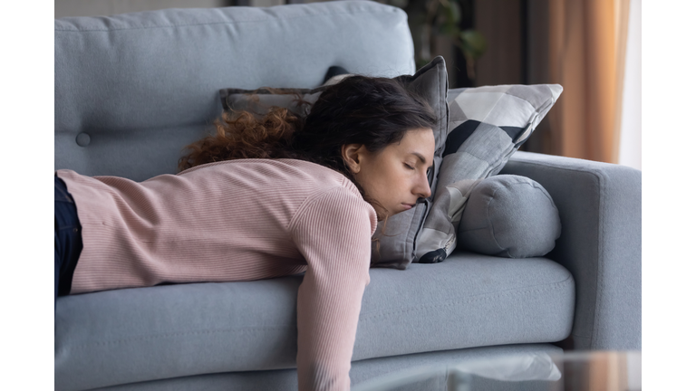 Tired young woman sleeping on couch at home