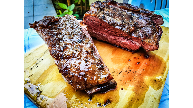 Close-up of argentine grilled ribs (asado argentino or costillar) on a wooden board