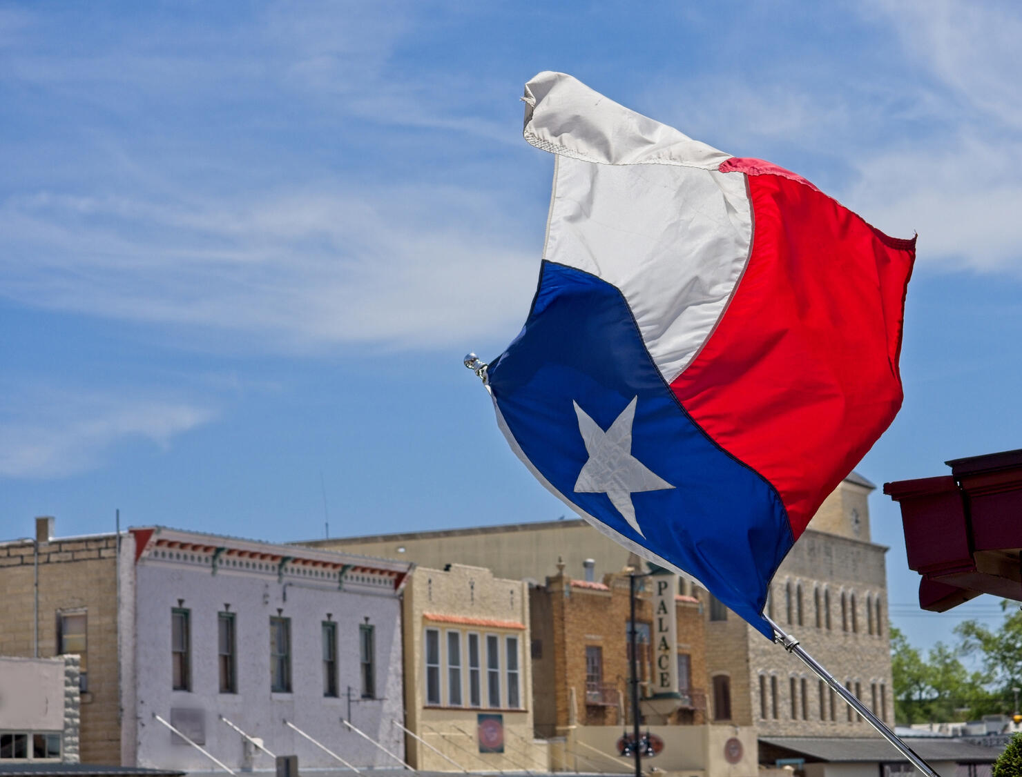 The Texas state flag flies over downtown Main street Fredericksburg Texas