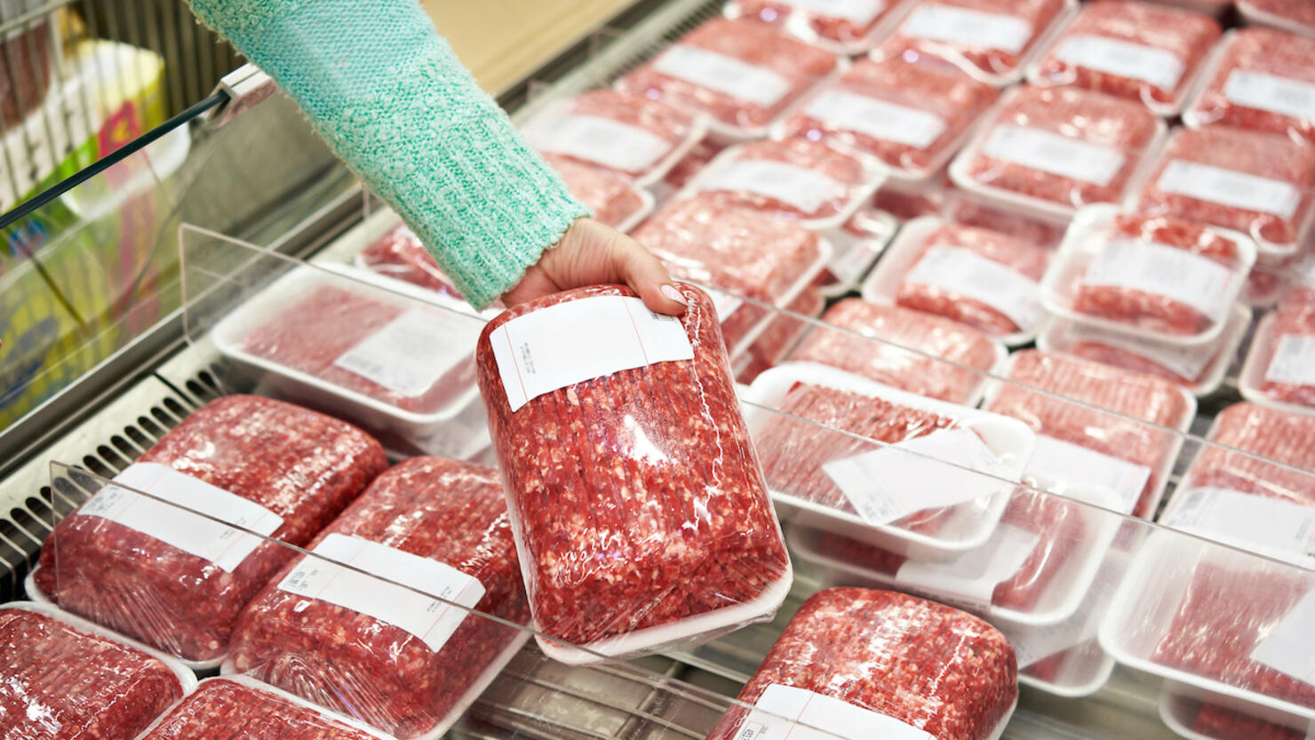 Buyer woman chooses chopped meat in shop