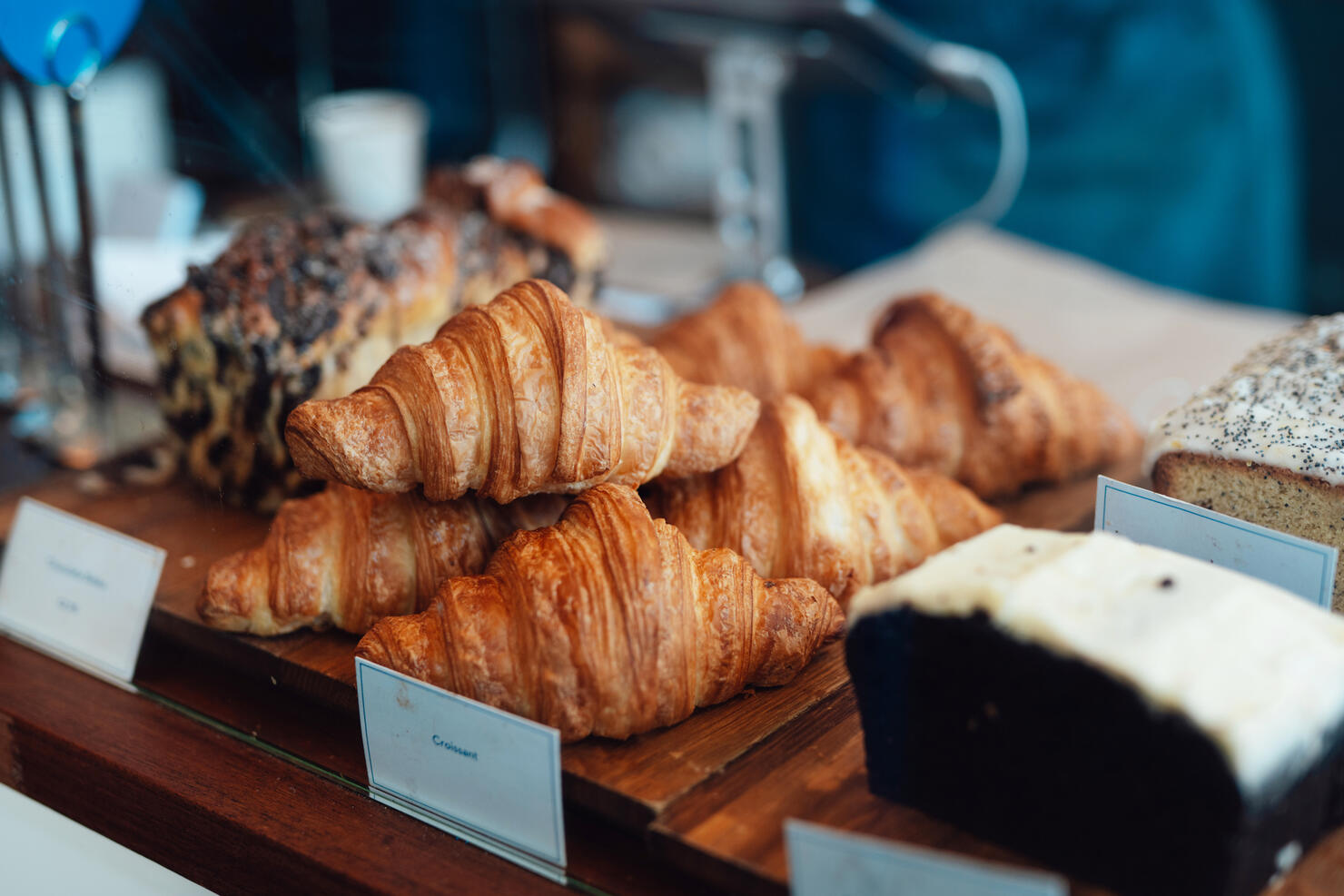 Close-up of fresh croissants and loaf cake displaying on counter at bakery