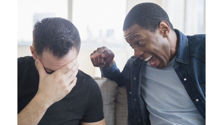 Close up of man teasing friend on sofa