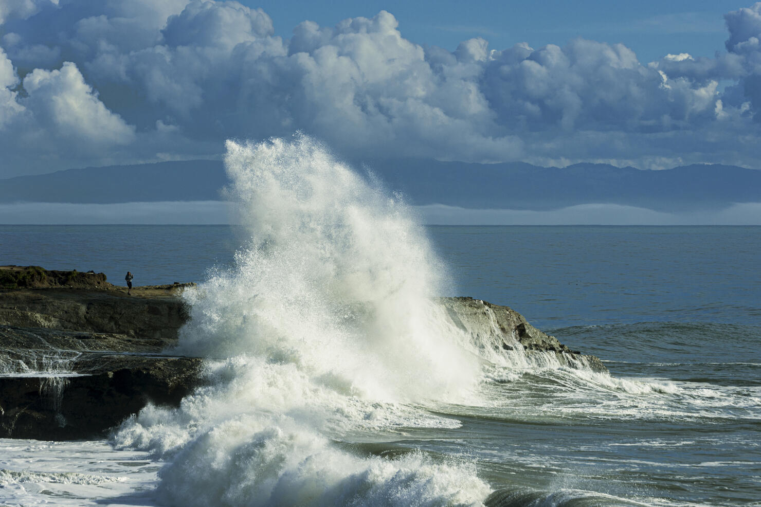 Larger Ocean Wave Crashing On Rocky Shore