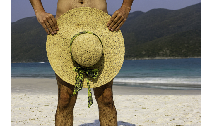 Man in nude beach with sun hat over instimate parts. Nudist concept