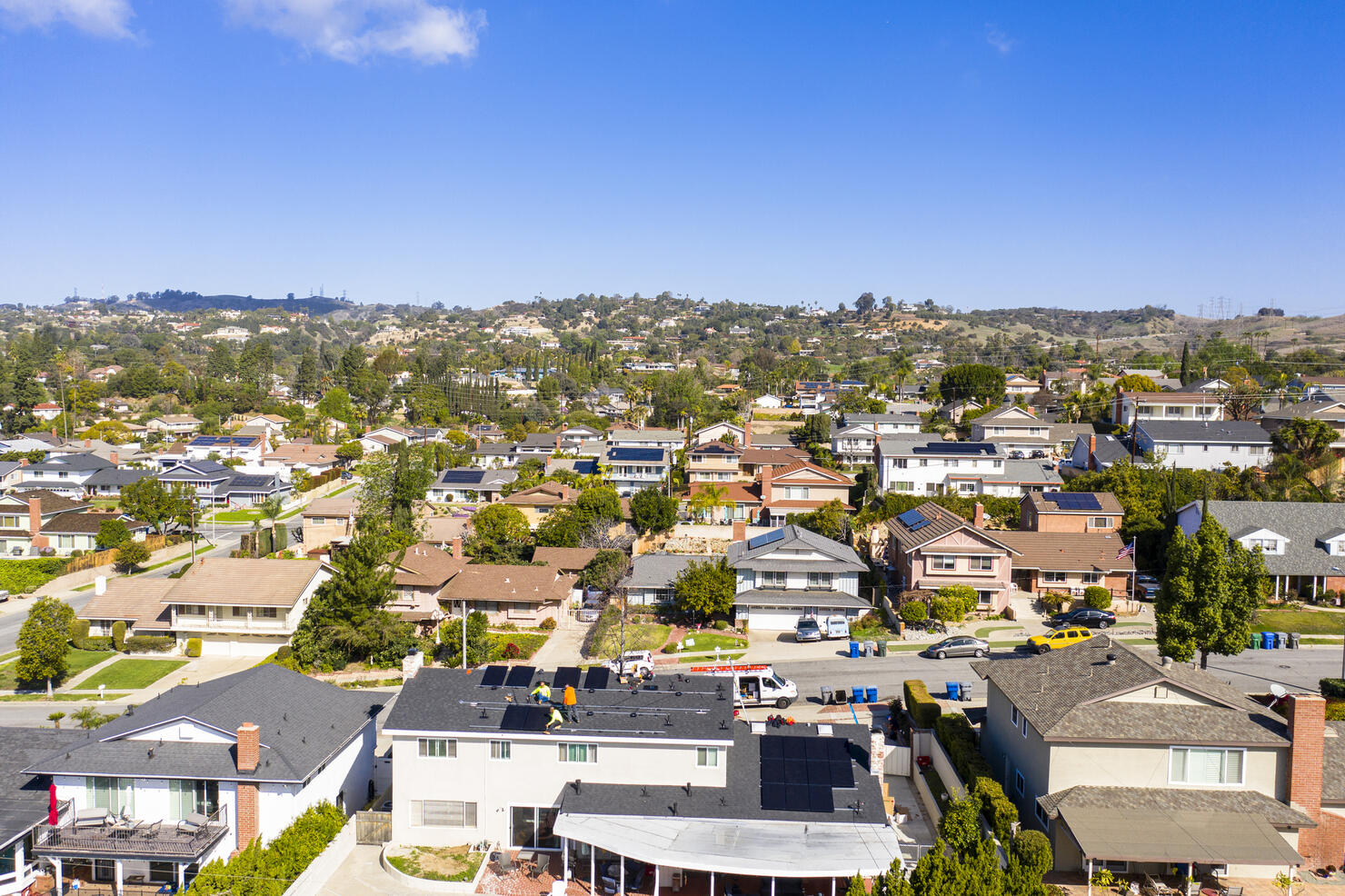 Wide View of Team of Workers Installing Solar Panels on Residential Rooftop in California