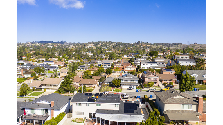 Wide View of Team of Workers Installing Solar Panels on Residential Rooftop in California