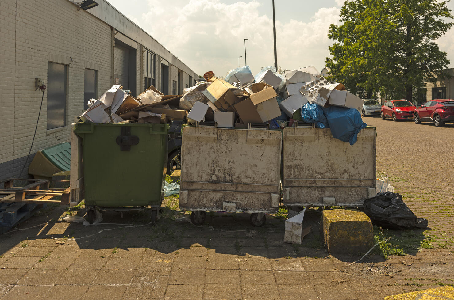 three waste containers filled to the brim with rubbish