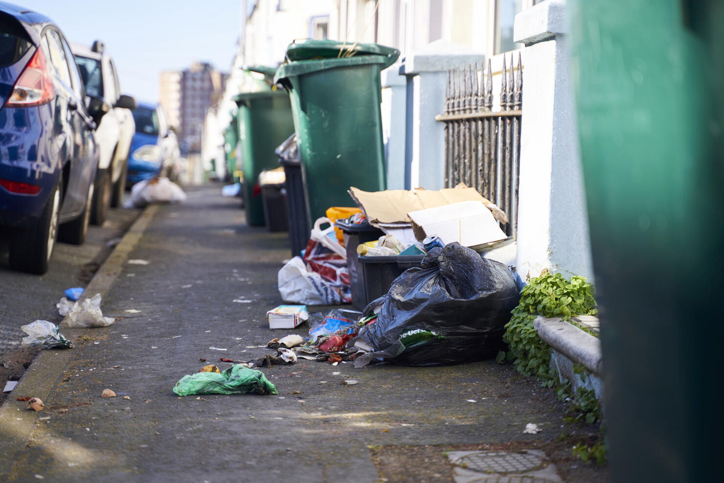 Trash in the street spilling on to the pavement