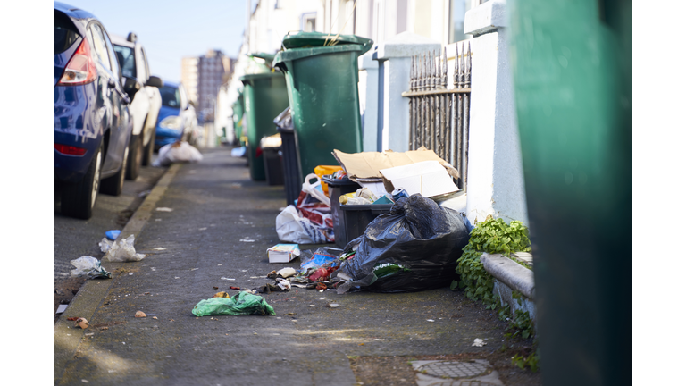 Trash in the street spilling on to the pavement