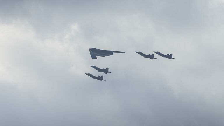 B-2 Stealth Bomber with escort of F-35 fighter jets fly over