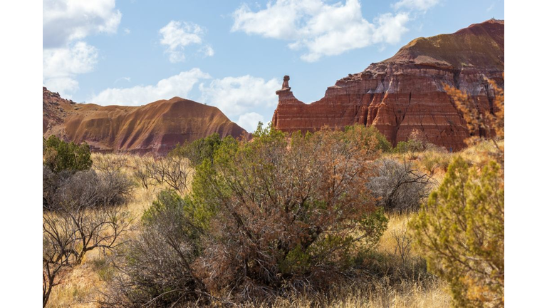 The Lighthouse rock hoodoo behind a field of grass and shrubs at Palo Duro Canyon State Park near Amarillo, Texas
