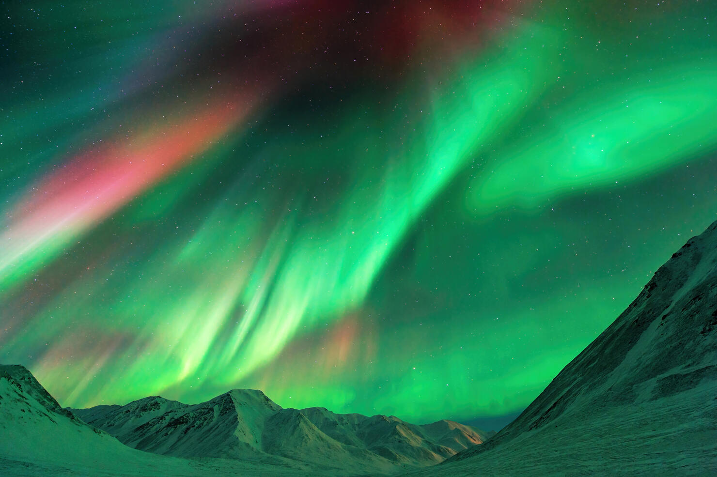 Strong geomagnetic Aurora Borealis (Northern Lights) dancing over the Alaskan peaks near Atigun Pass along the Dalton Highway, located to the north of Fairbanks, Alaska, USA.