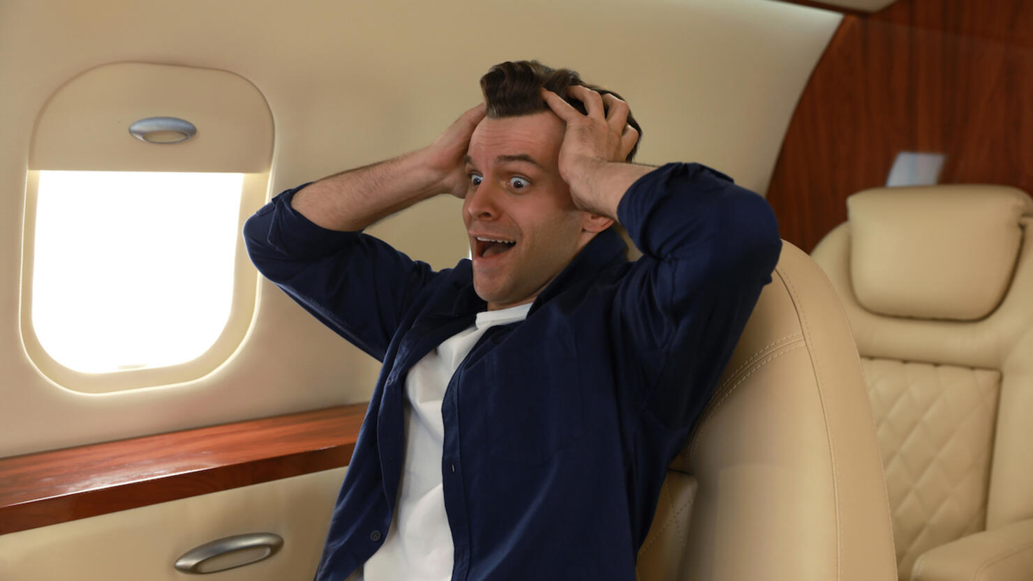 Scared young man suffering from aviophobia in airplane