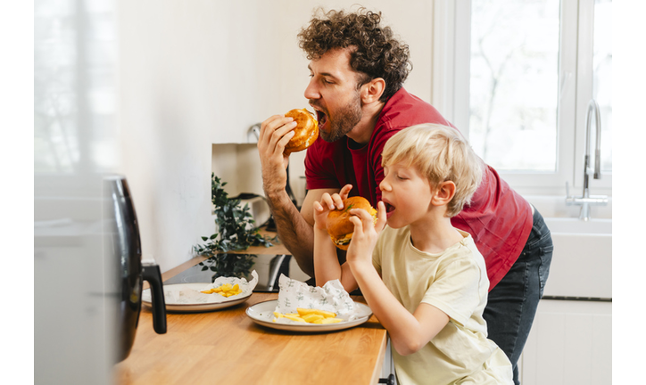 Father and son eating hamburger at home