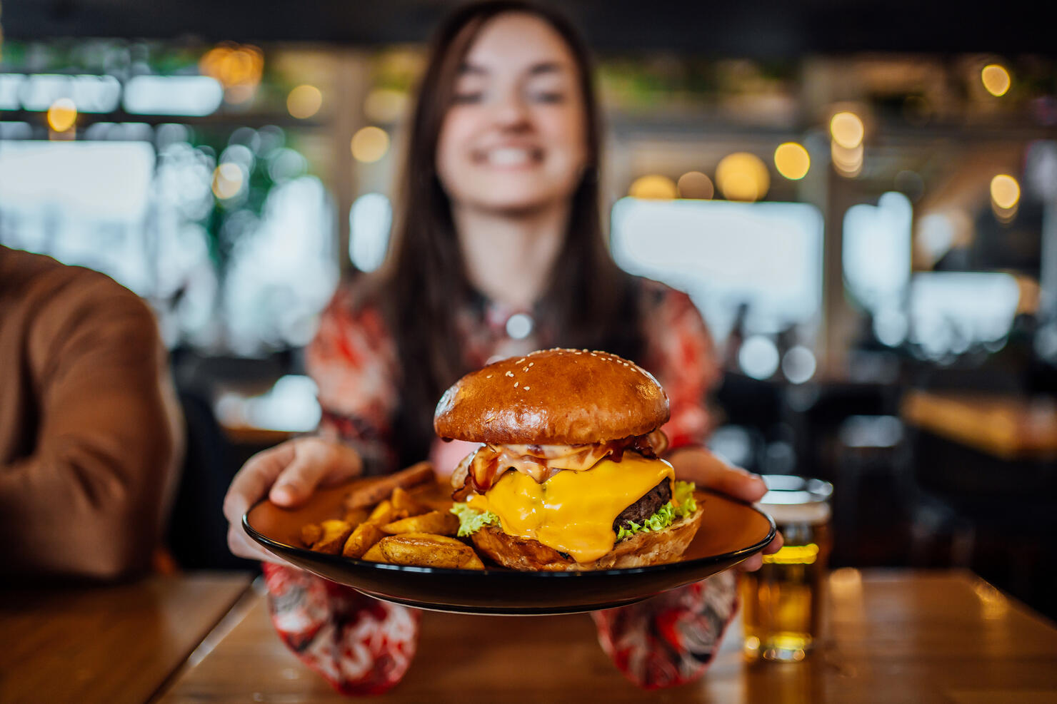 Young woman holding a plate with a tasty burger