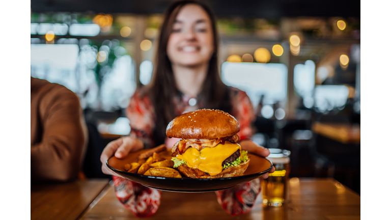Young woman holding a plate with a tasty burger
