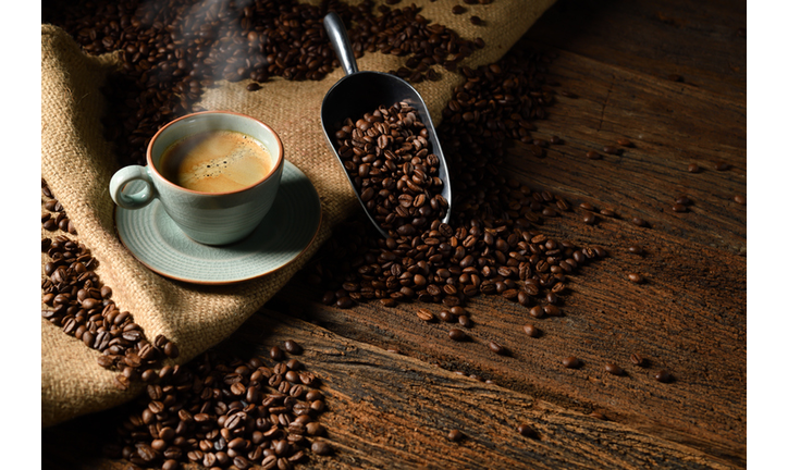 Cup of coffee with smoke and coffee beans on old wooden background