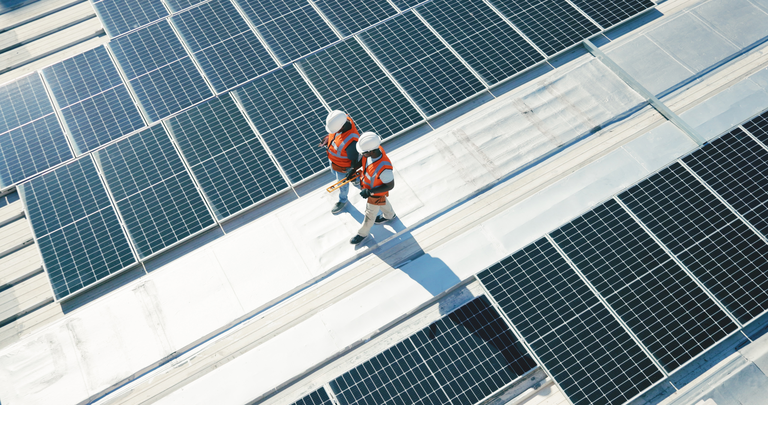 Renewable energy, solar panels and team walking on roof planning for inspection at sustainable business. Engineering, sustainability and photovoltaic power, men in electricity maintenance from above.