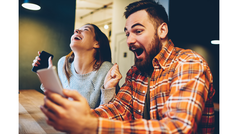 Excited male and female hipsters rejoice in winning an internet lottery made bets on website on modern smartphone.Happy couple in love celebrating victory in online competitions enjoying success