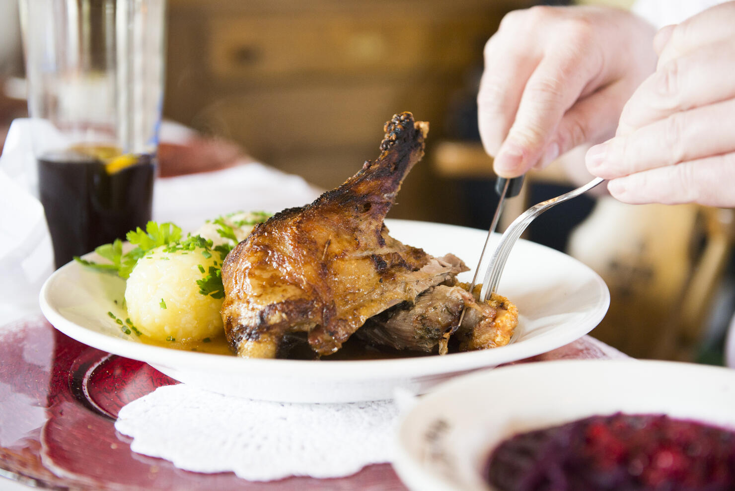 Man eating duck meat with potato dumpling at restaurant table, Bavaria, Germany
