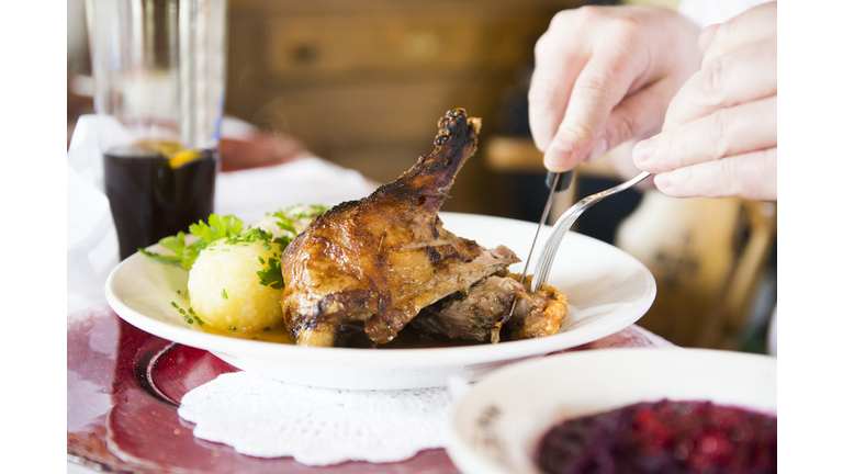 Man eating duck meat with potato dumpling at restaurant table, Bavaria, Germany
