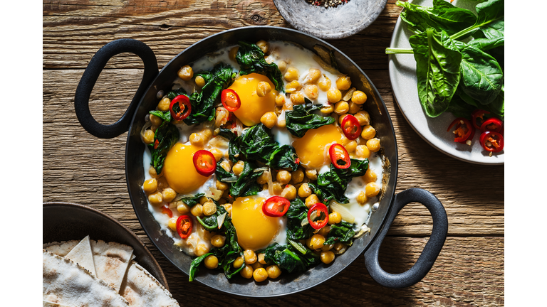 Chickpea and spinach shakshuka in cooking pan, sunlight with harsh shadows