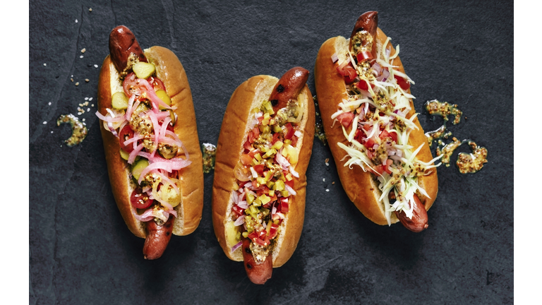 Three gourmet hot dogs on black background