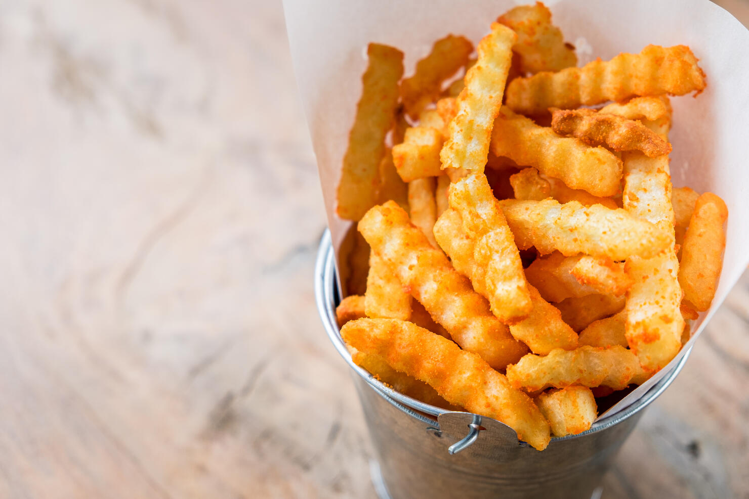 Fresh french fries in a basket on the wooden table background