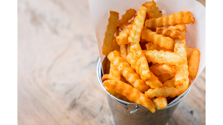 Fresh french fries in a basket on the wooden table background