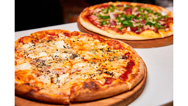 Pizza with salami, bell pepper, tomatoes and cheese, pickles, bacon and sausages on a light background. Close-up, selective focus