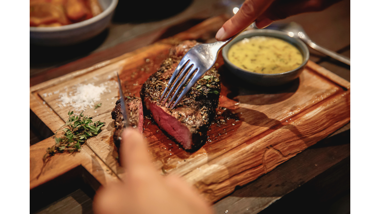 Unrecognizable Woman Eating Steak in High End Restaurant