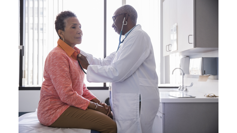 Smiling female doctor examining senior patient in hospital
