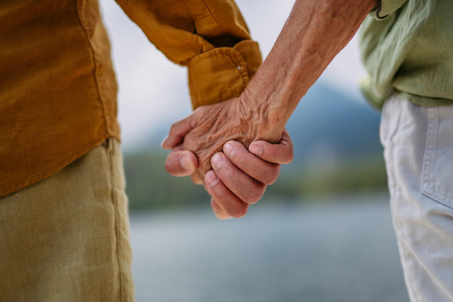 Close up of senior couple holding hands.