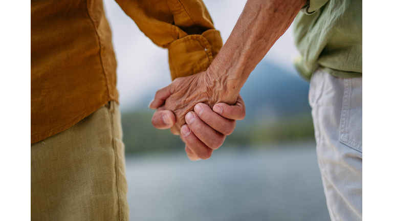 Close up of senior couple holding hands.