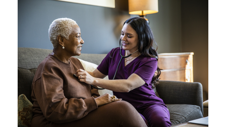 Nurse checking senior woman's vital signs in her home