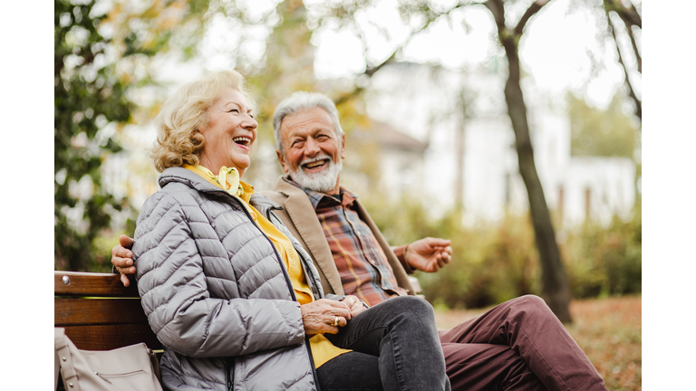 Happy senior couple sitting on the bench in park