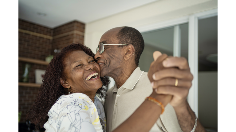 African American senior couple dancing on the balcony