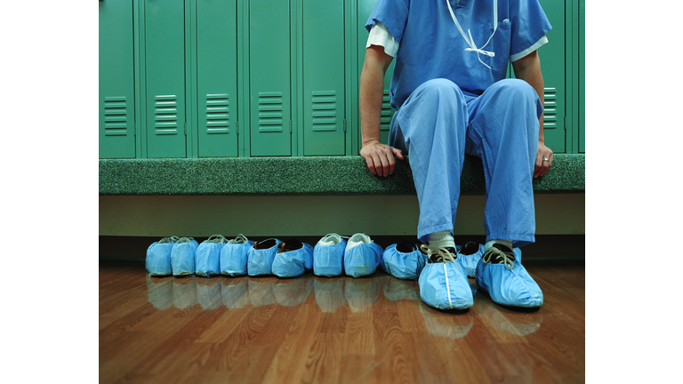 Medical worker wearing overshoes in locker room, low section