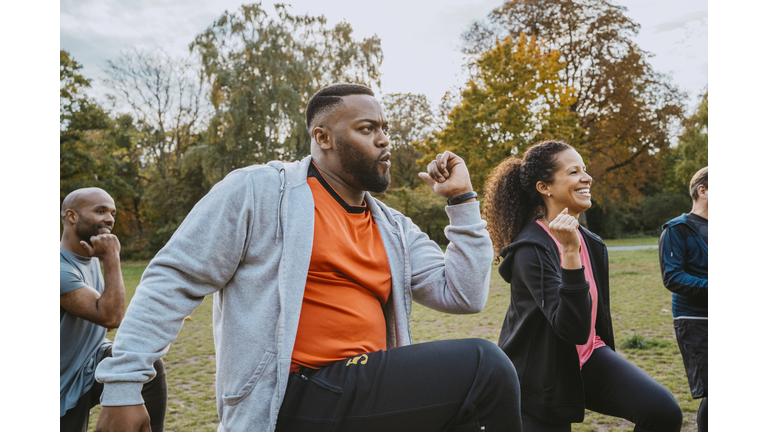 Multiracial male and female friends exercising in park
