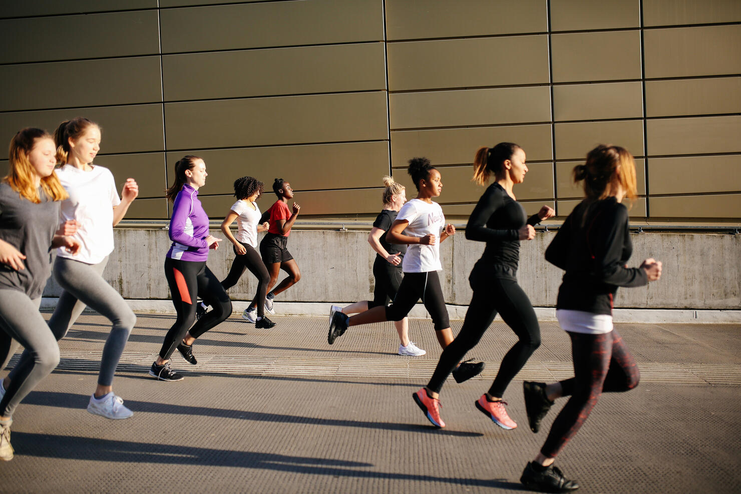 group of young women running in city setting