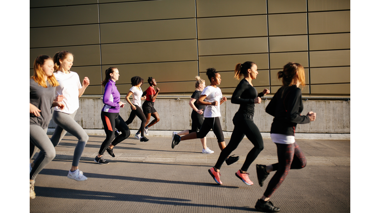 group of young women running in city setting