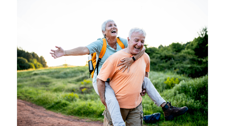 Playful mature couple piggybacking on a beautiful day in nature