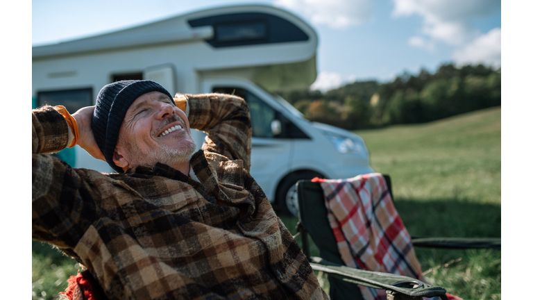 Senior man camping with caravan in nature.
