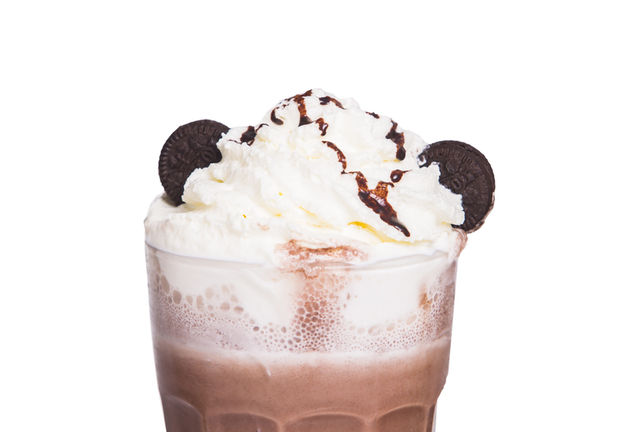 closeup of chocolate milkshake with cream and encrusted chocolate cookies