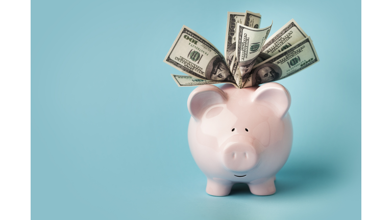 Pink piggybank stuffed with dollar bills