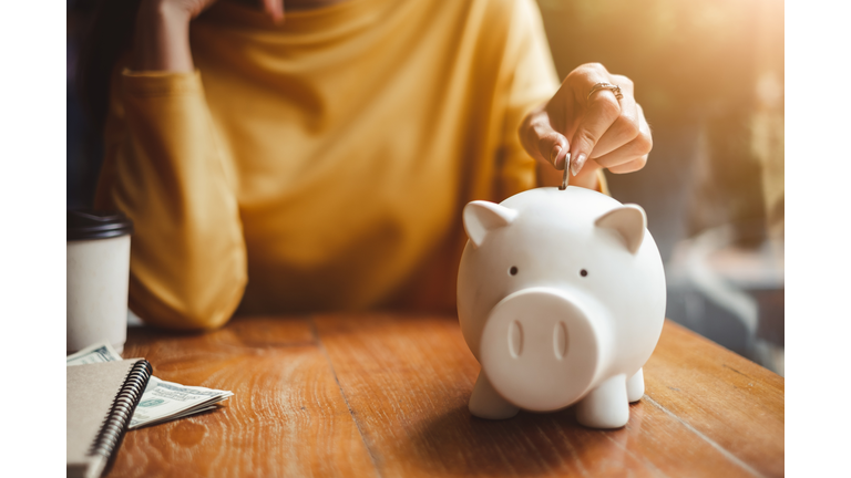 woman hand putting money coin into piggy for saving money wealth and financial concept.