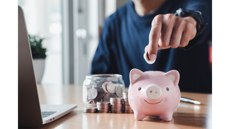 Hand putting coins in a piggy bank for save money and Saving Money concept.