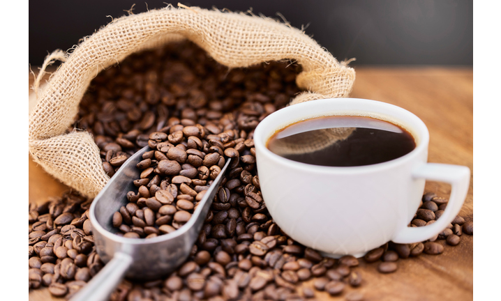 Shot of coffee beans and a cup of black coffee on a wooden table